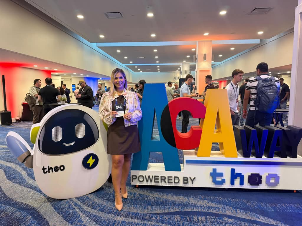 Dos asistentes posan junto a las letras de ACA Way y la mascota del evento en Miami.